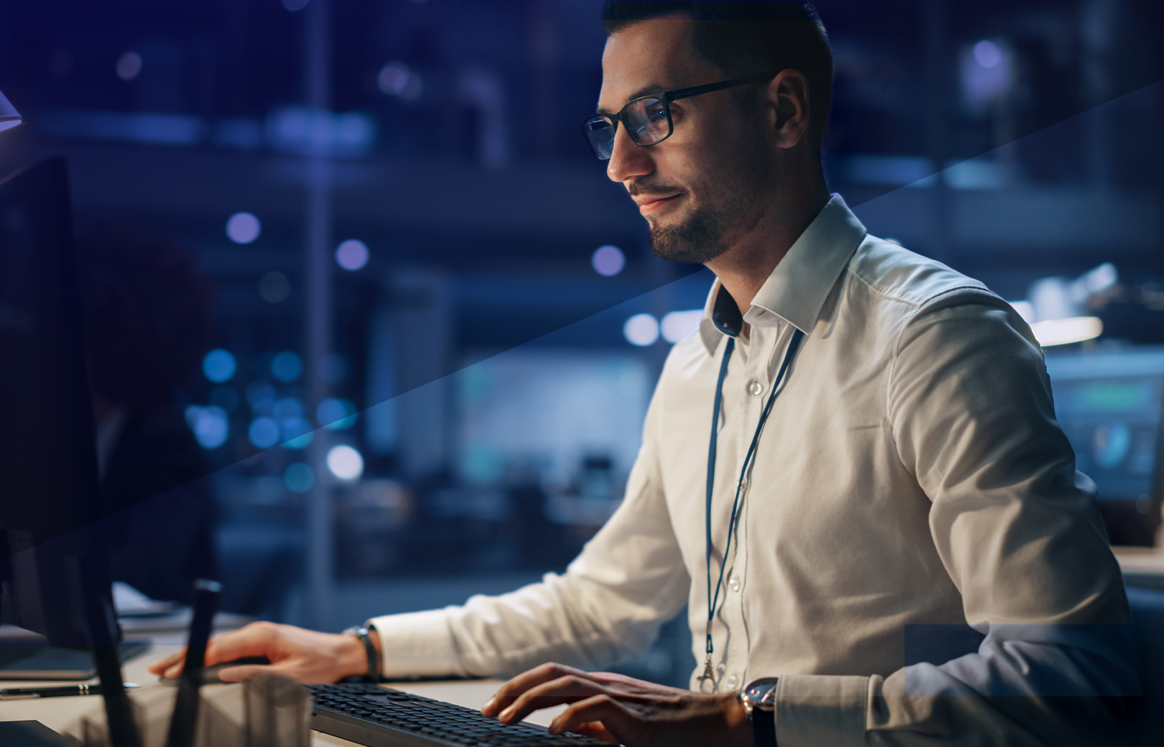 Imagem mostra um homem de camisa em frente ao seu computador