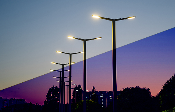 A imagem mostra postes de iluminação pública ao longo de uma estrada
